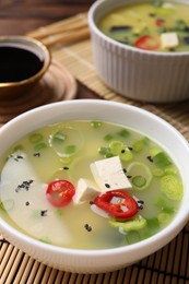 Photo of Bowls of delicious miso soup with tofu on table, closeup