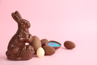 Photo of Chocolate Easter bunny and eggs on pink background. Space for text