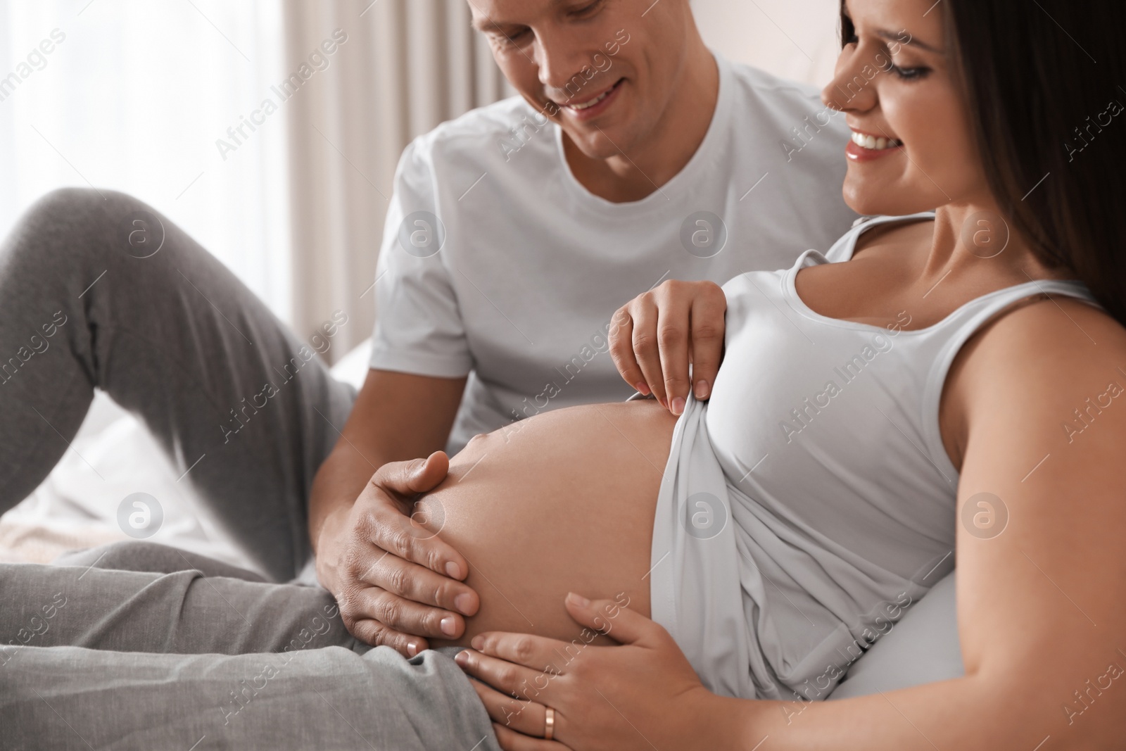 Photo of Young pregnant woman with her husband indoors, closeup