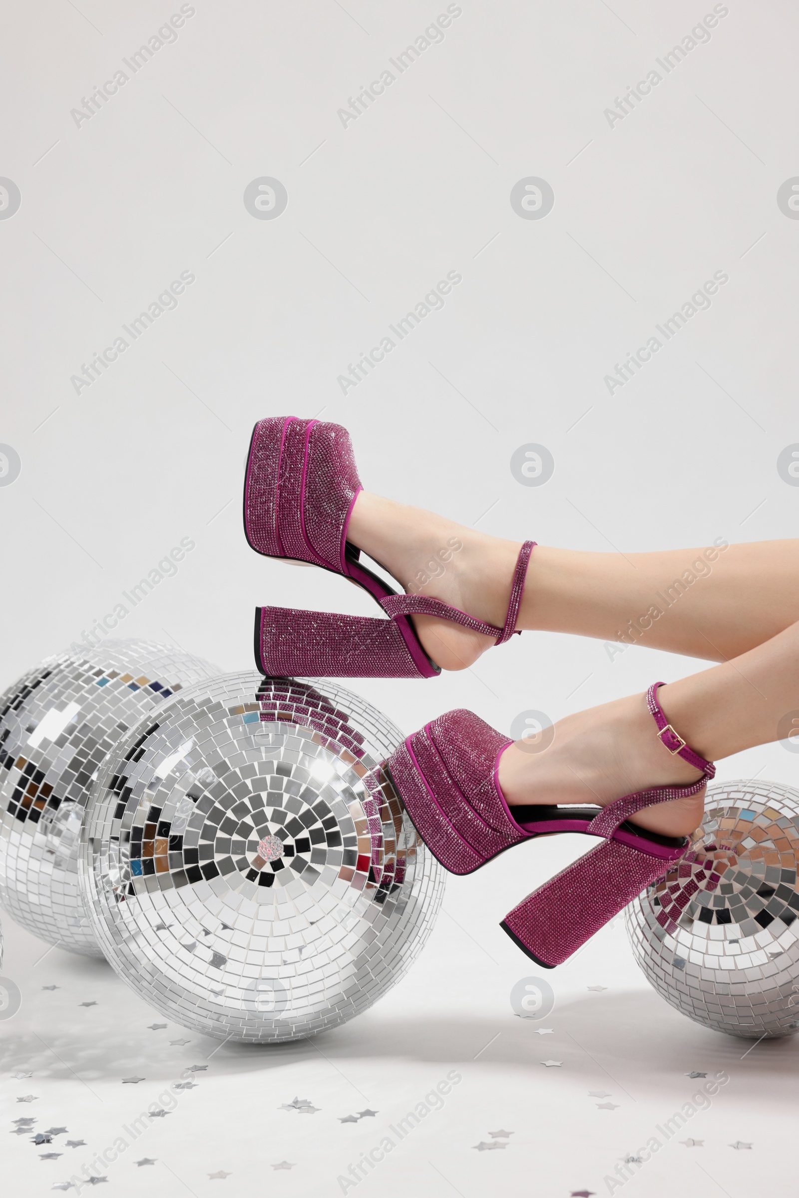 Photo of Woman in pink high heeled shoes and disco balls on white background, closeup