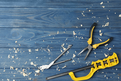 Modern carpenter's tools and shavings on blue wooden background, flat lay. Space for text