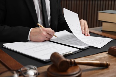 Photo of Lawyer working with documents at wooden table in office, closeup