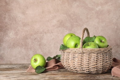 Photo of Composition with juicy green apples in wicker basket on table. Space for text