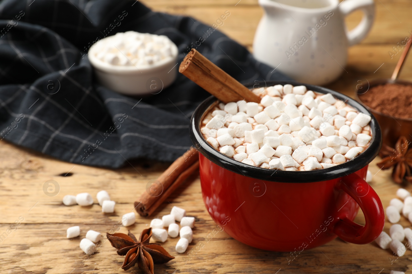 Photo of Tasty hot chocolate with marshmallows and ingredients on wooden table, closeup