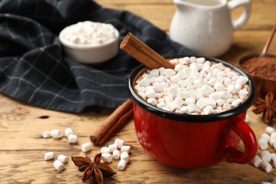 Photo of Tasty hot chocolate with marshmallows and ingredients on wooden table, closeup