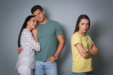 Photo of Unhappy woman feeling jealous while couple spending time together on grey background