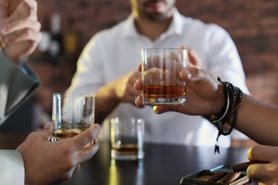 Group of friends drinking whiskey together in bar, closeup