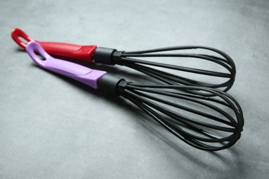 Photo of Two whisks on gray table, closeup. Kitchen tool