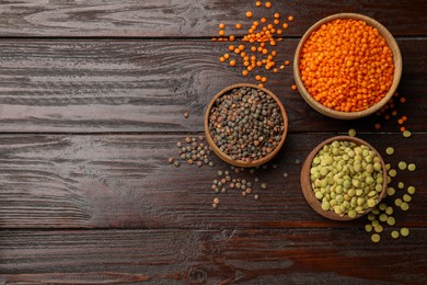 Photo of Different types of lentils in bowls on wooden table, flat lay. Space for text