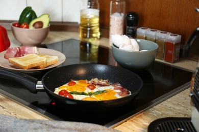 Photo of Tasty eggs with tomatoes and bacon in frying pan for breakfast
