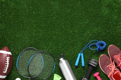 Photo of Different sport tools on green grass, flat lay. Space for text