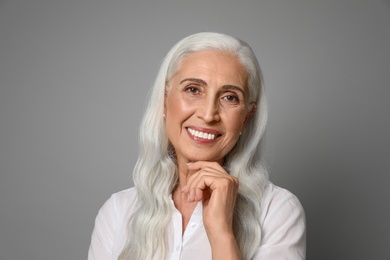 Portrait of beautiful mature woman on grey background