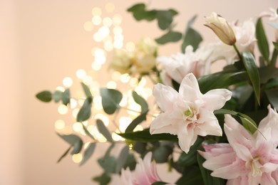 Photo of Bouquet of beautiful lily flowers against beige background with blurred lights, closeup. Space for text