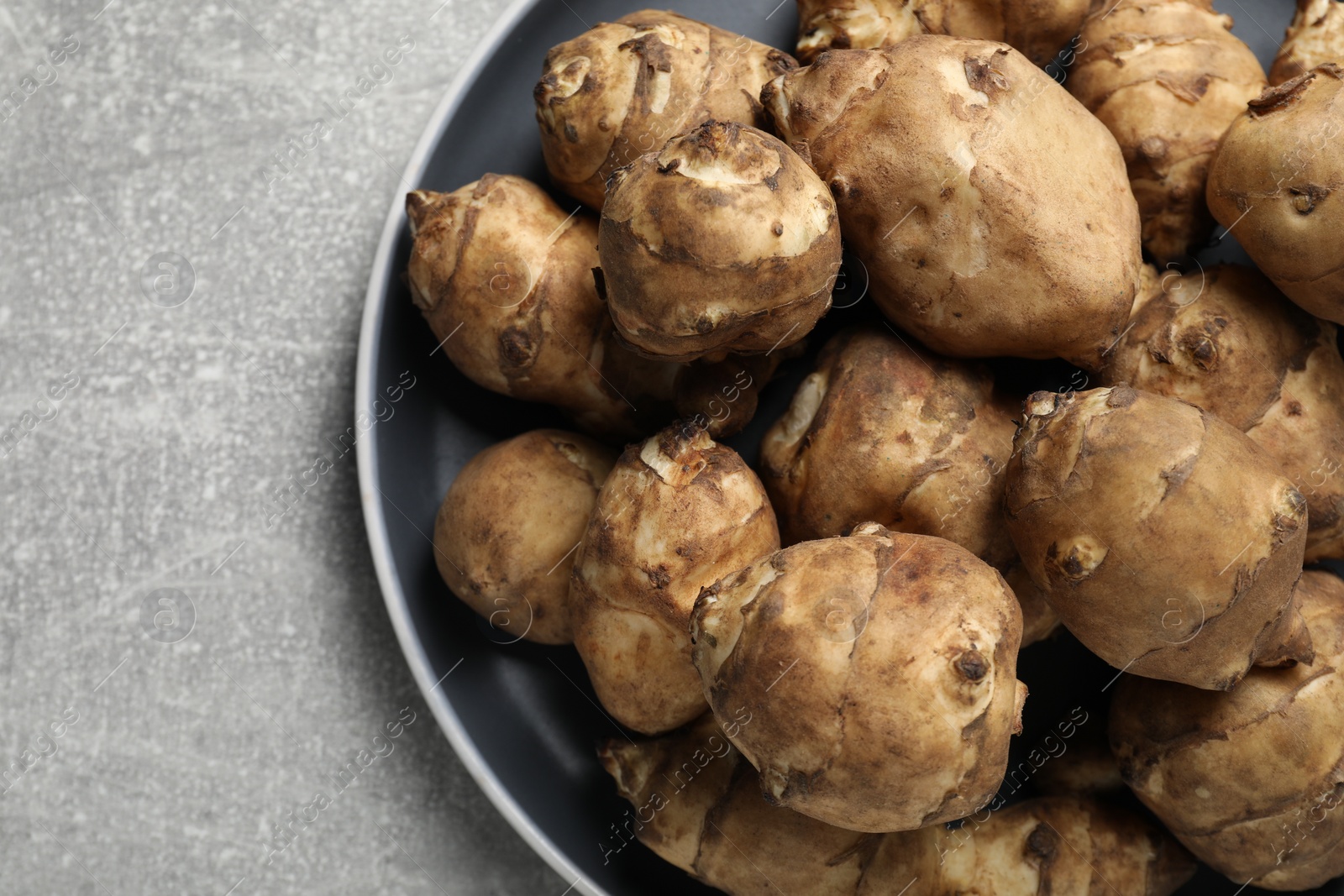 Photo of Jerusalem artichokes on light grey table, top view. Space for text
