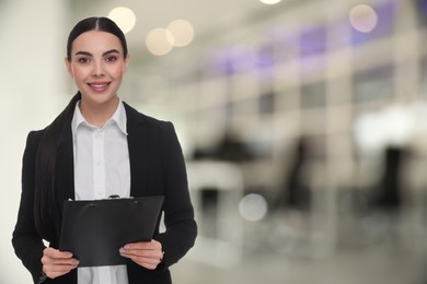 Lawyer, consultant, business owner. Confident woman with clipboard smiling indoors, space for text