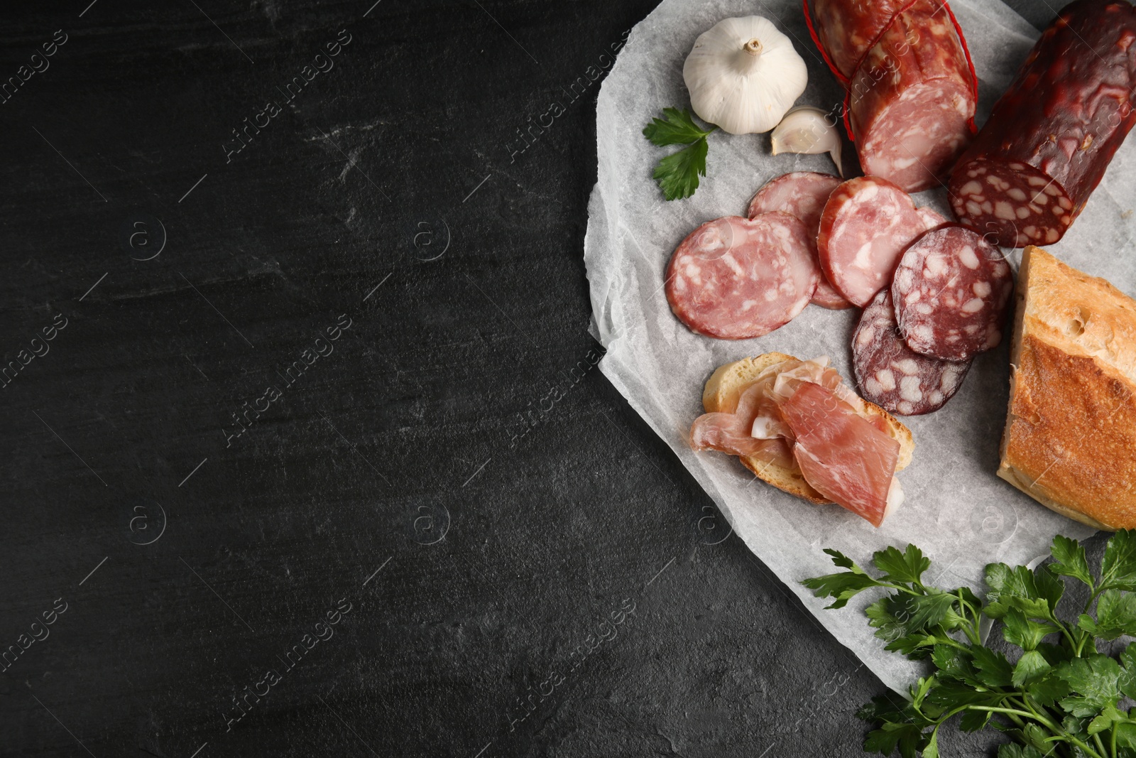 Photo of Different types of sausages and bread on black table, flat lay. Space for text