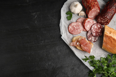 Different types of sausages and bread on black table, flat lay. Space for text