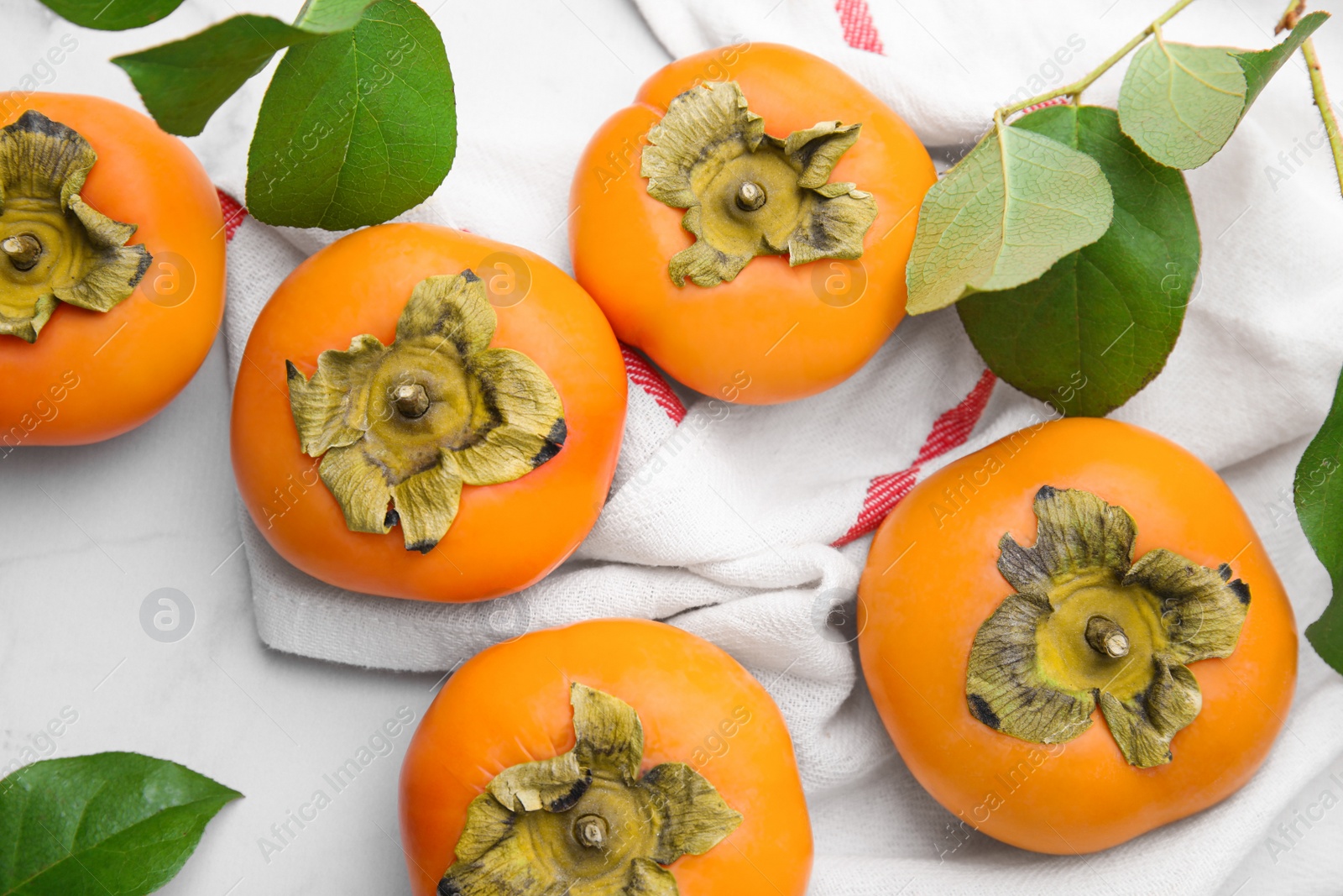 Photo of Delicious ripe juicy persimmons on white marble table, flat lay