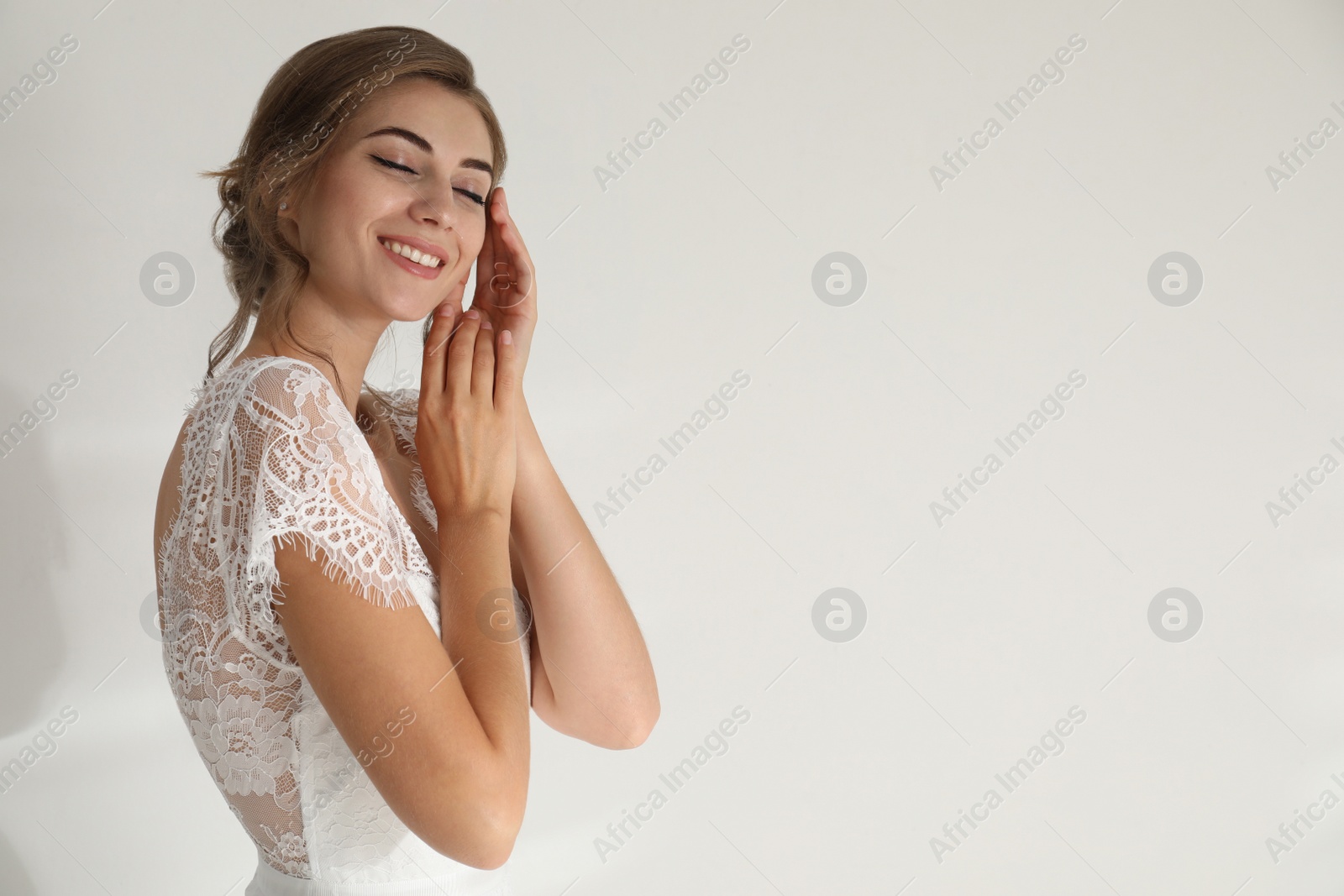 Photo of Young bride wearing beautiful wedding dress on light background. Space for text