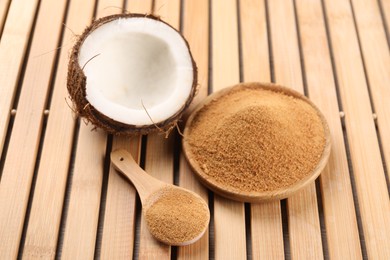 Photo of Coconut sugar, spoon, plate and fruit on wooden table, closeup