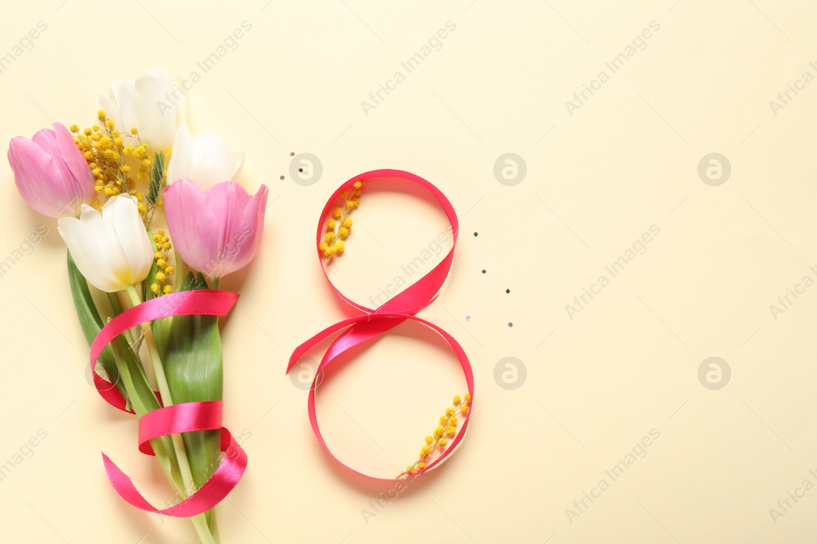 Photo of 8th of March greeting card design with red ribbon, beautiful flowers and space for text on beige background, flat lay. International Women's day