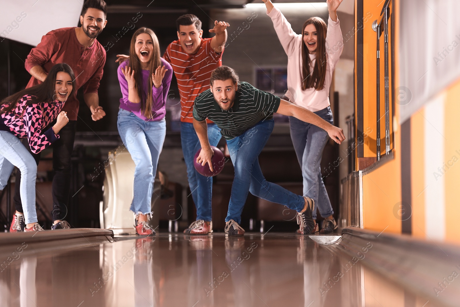 Photo of Young man throwing ball and spending time with friends in bowling club