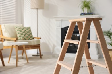 Wooden folding ladder in stylish living room. Space for text