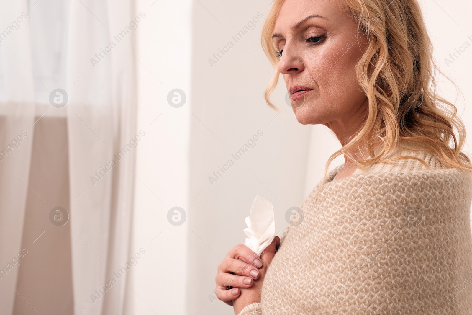 Photo of Upset middle aged woman with paper tissue at home, space for text. Loneliness concept