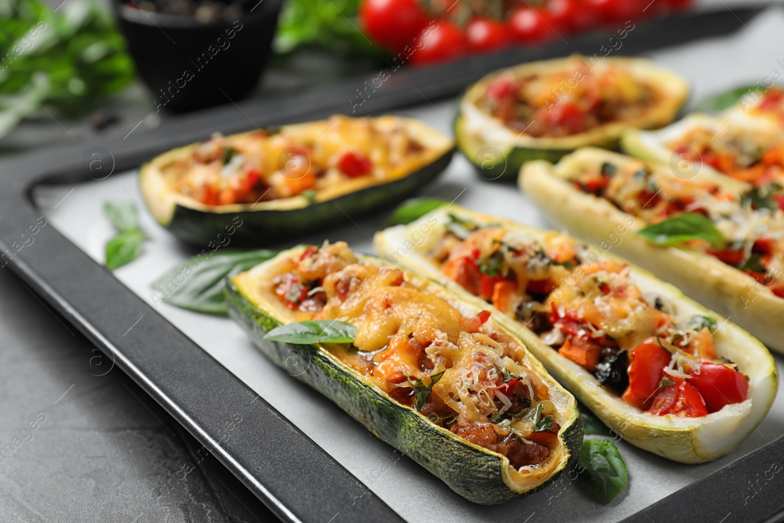 Photo of Baking tray of delicious stuffed zucchini  on grey table, closeup