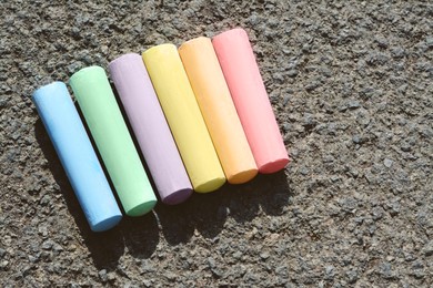 Colorful chalk sticks on asphalt, flat lay. Space for text