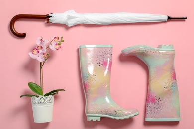 Photo of Flat lay composition with umbrella and rubber boots on color background