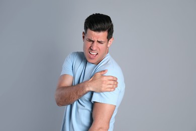 Photo of Man suffering from shoulder pain on grey background