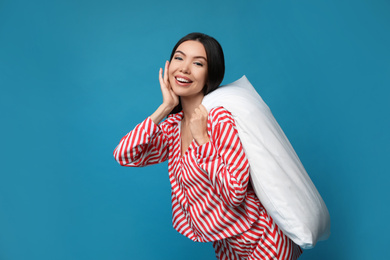 Beautiful Asian woman with pillow on blue background. Bedtime