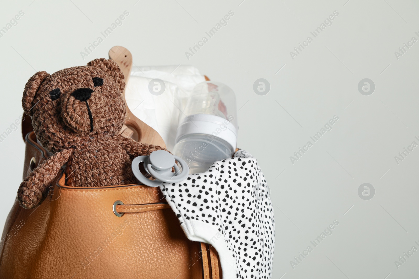 Photo of Mother's bag with baby's stuff on light grey background. Space for text