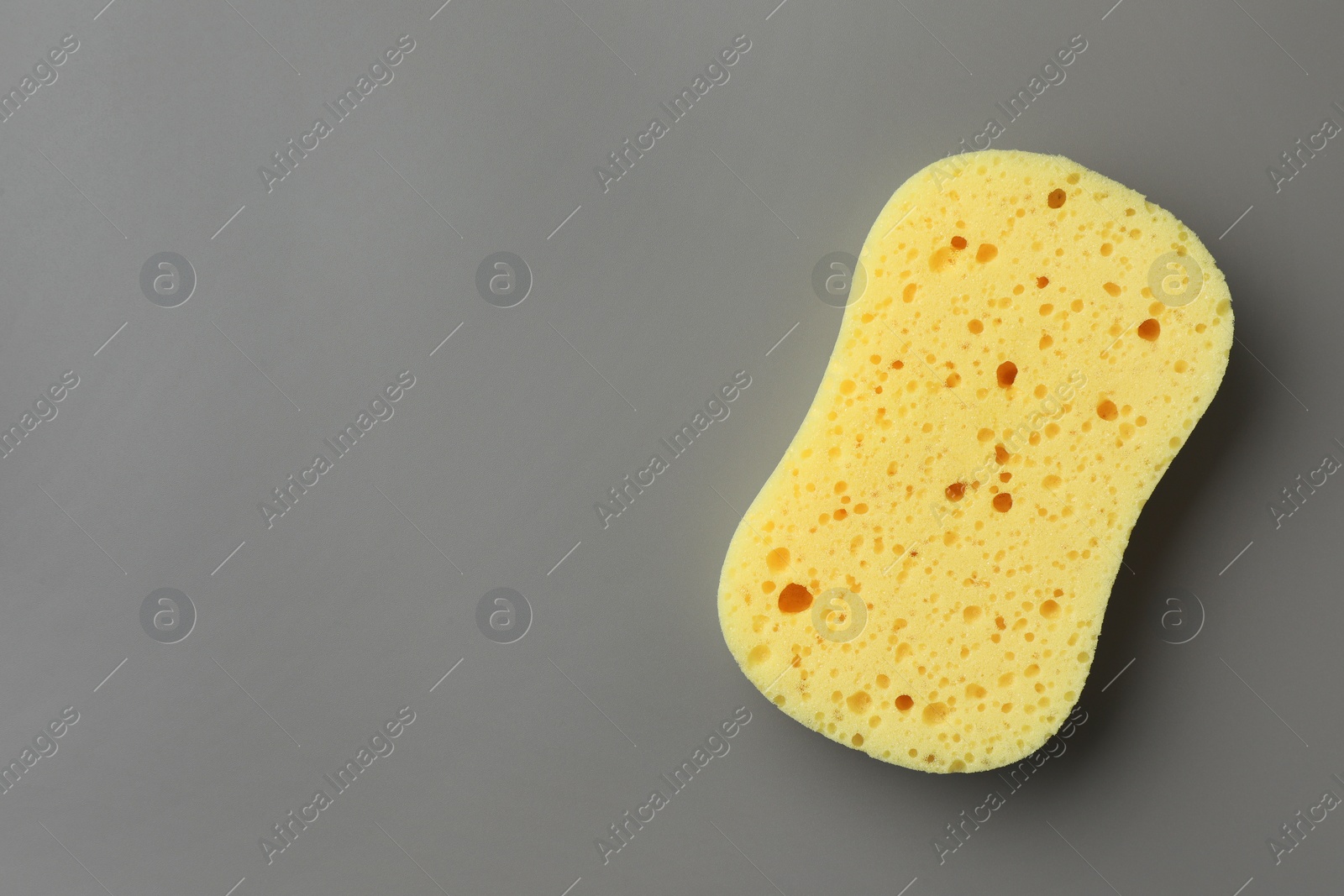 Photo of New yellow sponge on grey background, top view. Space for text