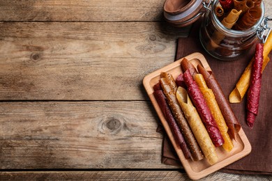 Delicious fruit leather rolls on wooden table, flat lay. Space for text