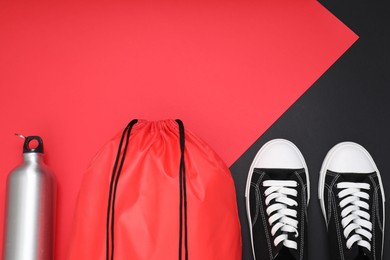 Photo of Red drawstring bag, thermo bottle and sneakers on color background, flat lay. Space for text