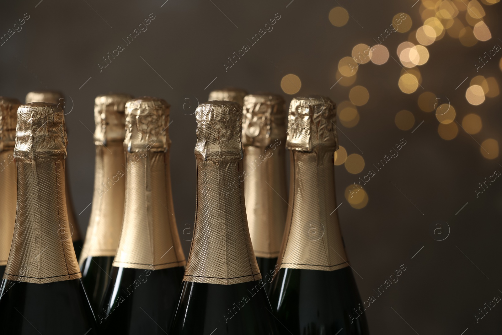 Photo of Many bottles of champagne on blurred background, closeup. Space for text