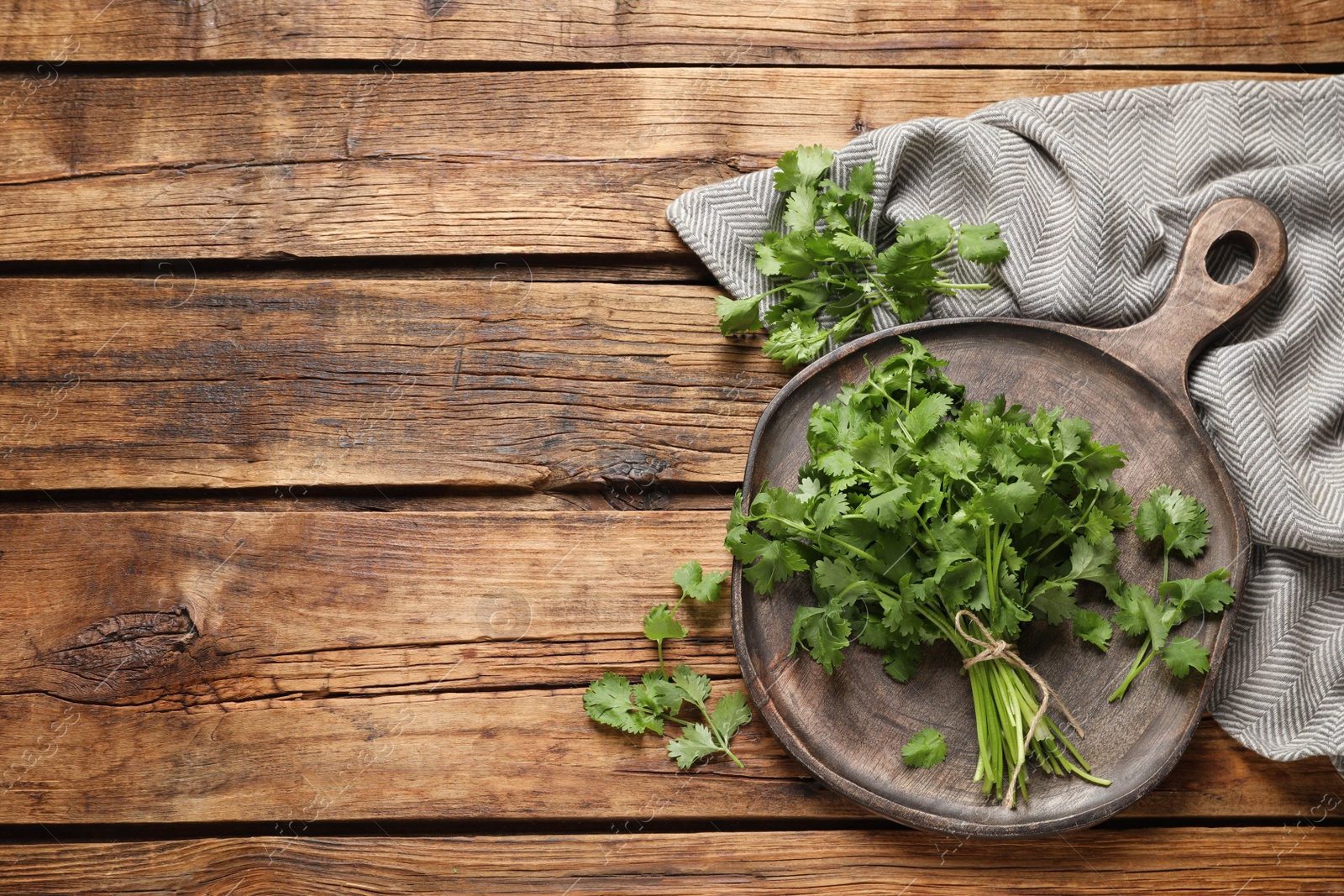 Photo of Bunch of fresh aromatic cilantro on wooden table, flat lay. Space for text