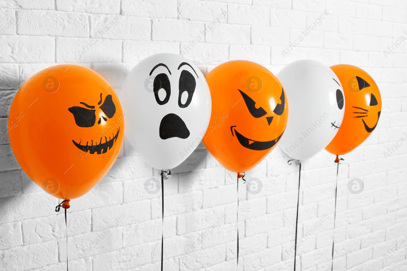 Photo of Color balloons for Halloween party against white brick wall