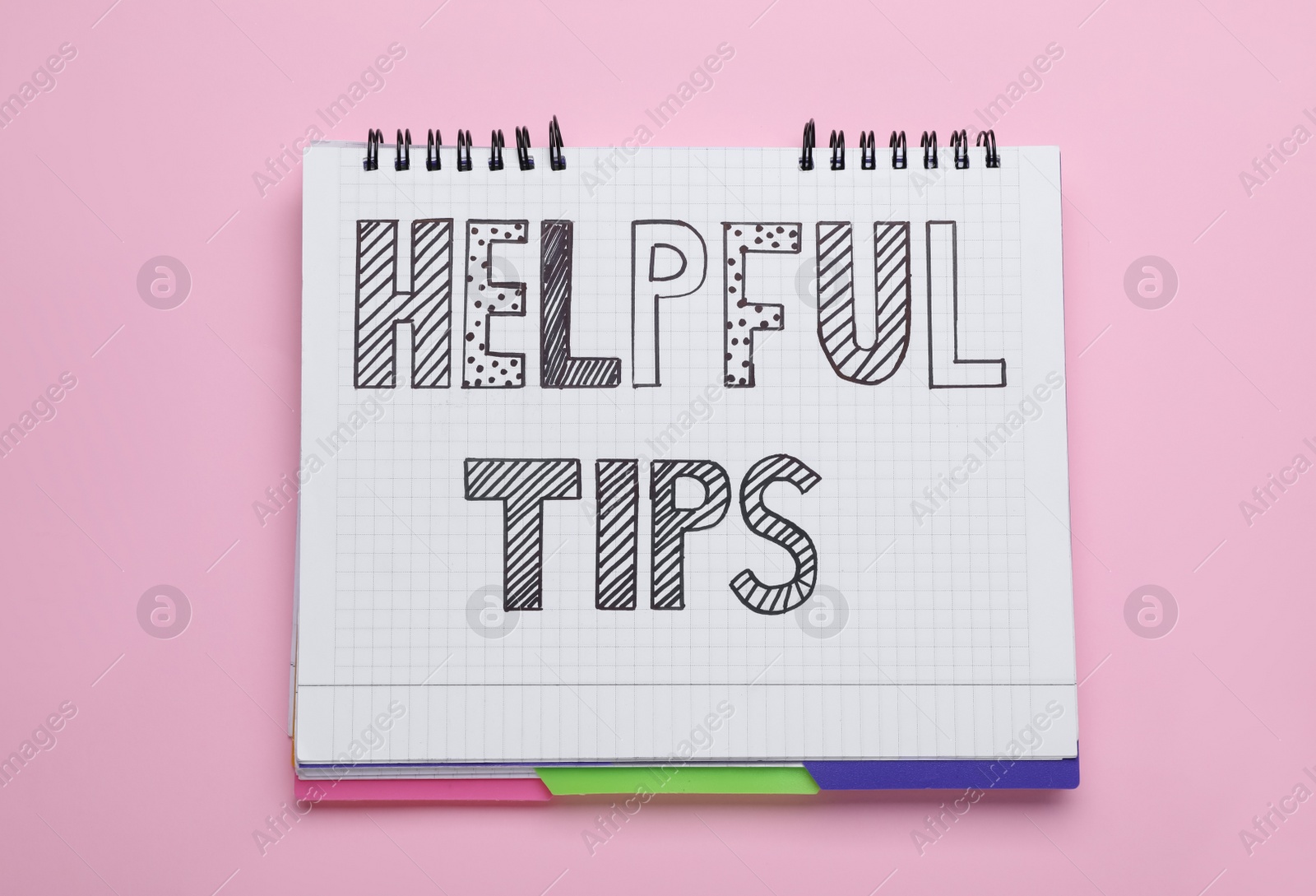 Photo of Phrase Helpful Tips in notebook on pink background, top view