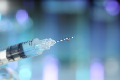 Photo of Syringe with medicine against blurred background, closeup. Space for text