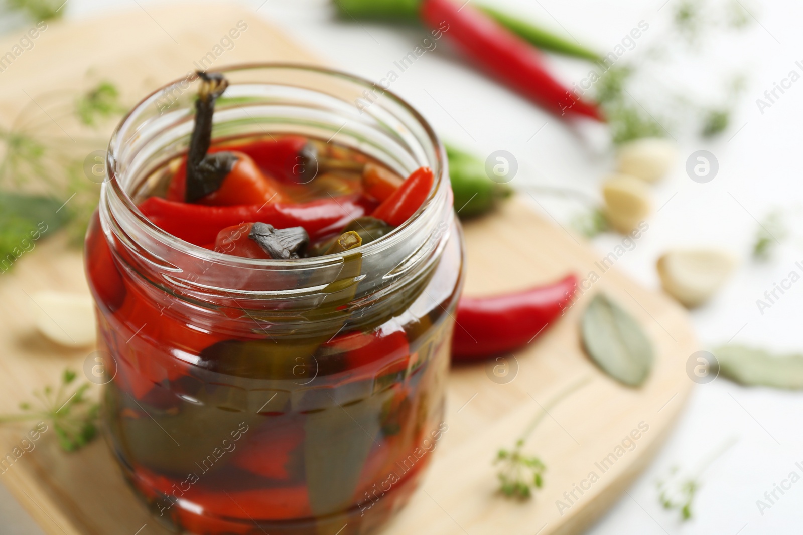 Photo of Glass jar of pickled chili peppers on table, closeup. Space for text