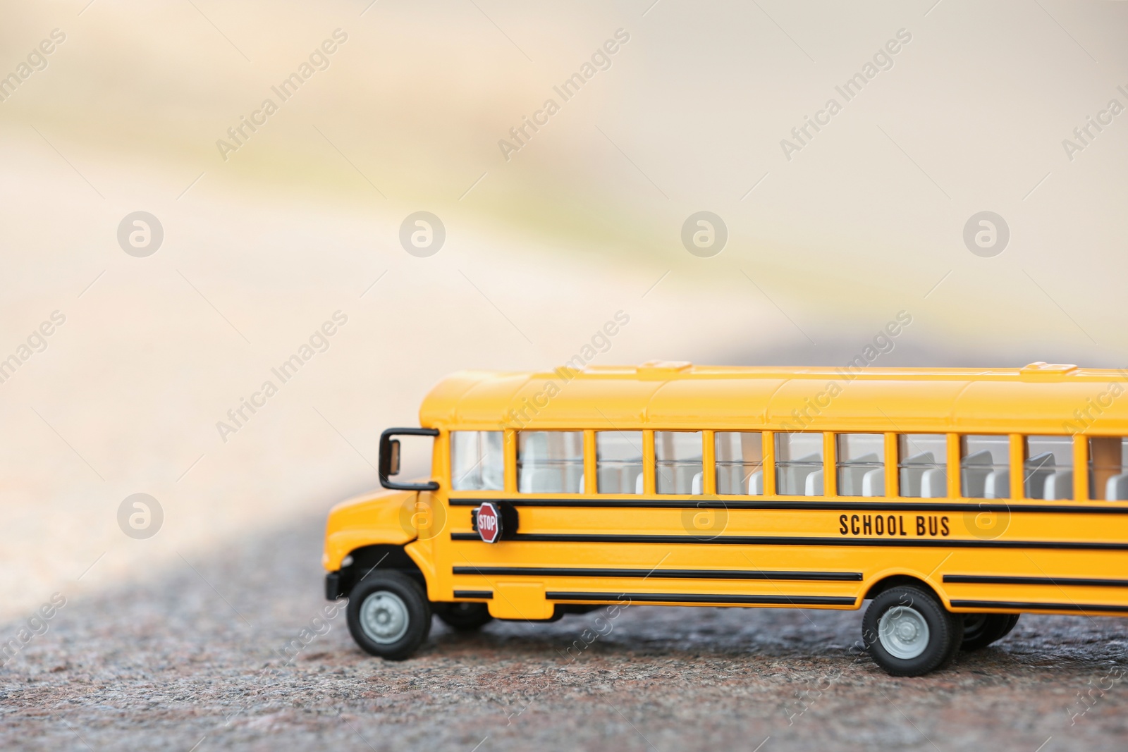 Photo of Yellow toy school bus on road outdoors. Student's transport