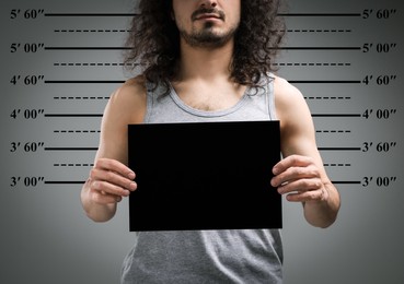 Criminal mugshot. Arrested man with blank card against height chart, closeup