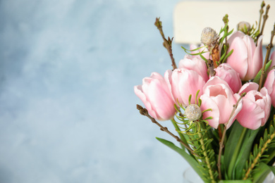 Photo of Beautiful bouquet with spring pink tulips on light blue background, closeup. Space for text