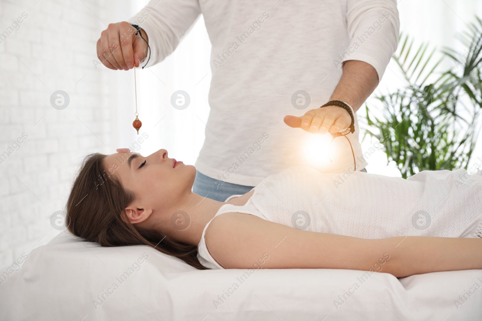 Photo of Young woman during crystal healing session in therapy room