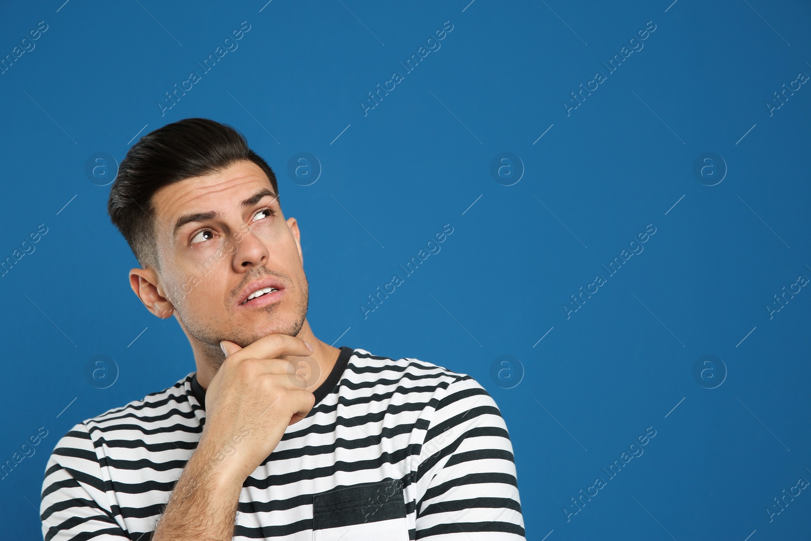 Photo of Pensive man on blue background, space for text. Thinking about answer to question
