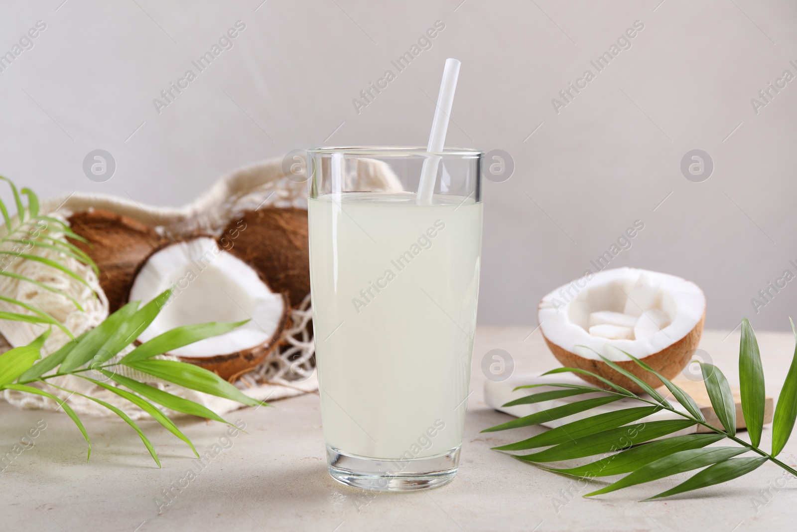 Photo of Glass of coconut water, palm leaves and nuts on light table