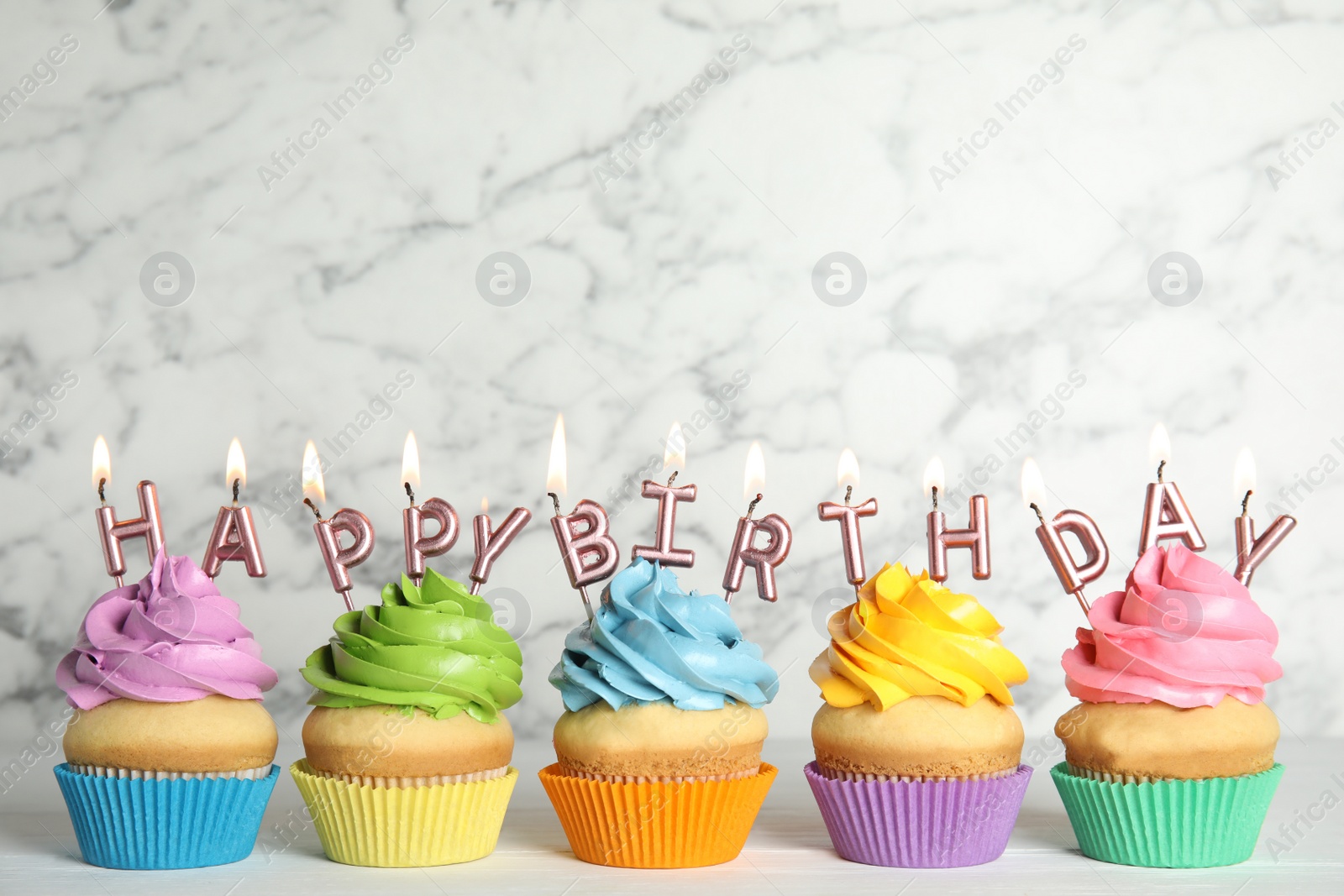 Photo of Birthday cupcakes with burning candles on table against marble background. Space for text